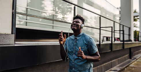Imagen de hombre caminando alegremente mientras escucha música.